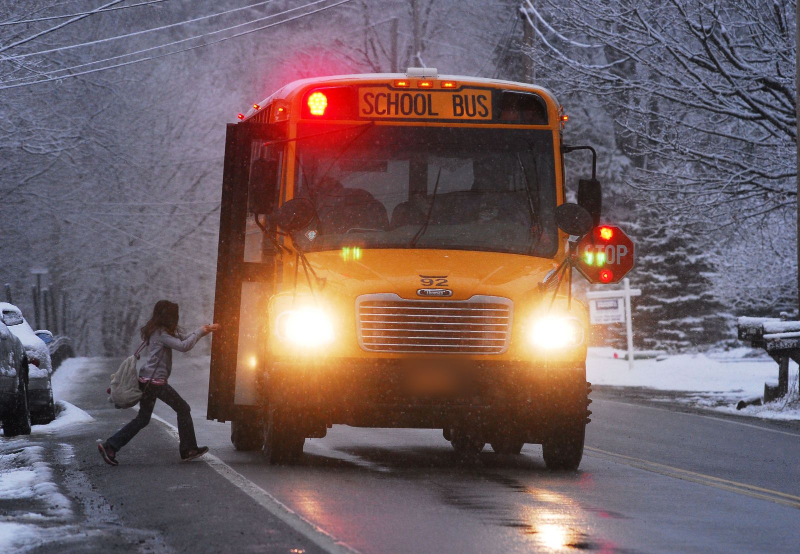 A child boarding a school bus on a snowy street